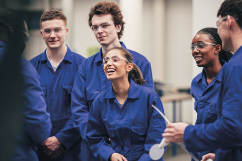 group of young employees in boiler suits laughing and smiling